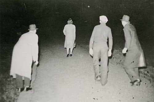 Tre mænd forfølger kvinde påmørk vej. Billedet stammer fra en arrangeret serie på 9 billeder, som angiveligt viser afstraffelse og klipning af tyskerpige.