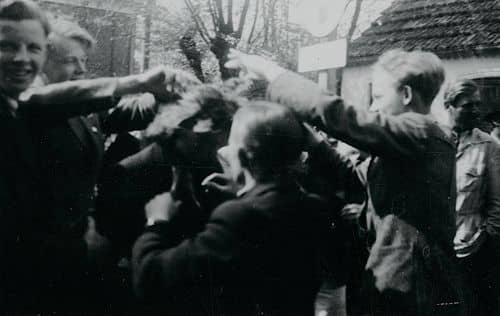 En gruppe mennesker står rundt om en tyskerpige, som  klippes efter befrielsen. Ukendt sted.