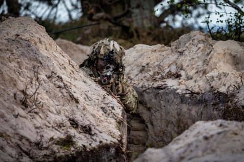 En soldat i camouflageuniform i en skyttegrav på Bornholm under en militær øvelse. Øens strategiske placering i Østersøen har øget den militære aktivitet i området.