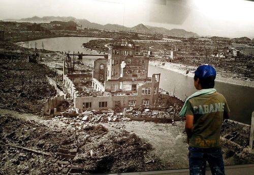 En dreng kikker på et kæmpe foto af den japanske by Hiroshima som blev ødelagt af den atombombe USA kastede ved krigens slutning.