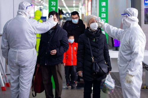 Togpassagerer i den kinesiske by Nanjing får målt deres temperatur af sundhedspersonale i beskyttelsesdragter. 18. februar 2020.