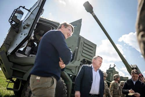 Lars Løkke Rasmussen og Troels Lund Poulsen besøger Bohdana-artillerisystem i Ukraine i foråret 2024. Soldater og militært materiel ses i baggrunden.