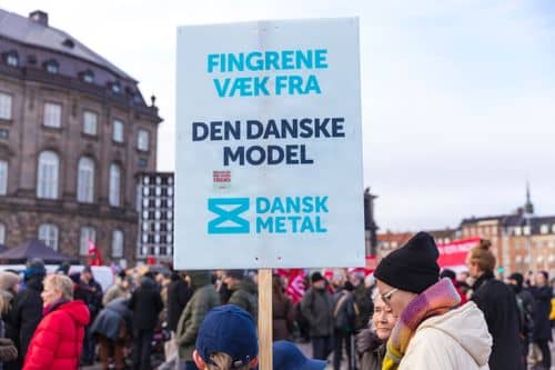Skilt ved demonstration med teksten "Fingrene væk fra den danske model"