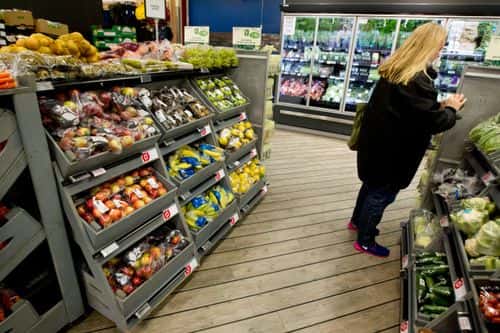 Kvinde i supermarked ved de økologiske grøntsager