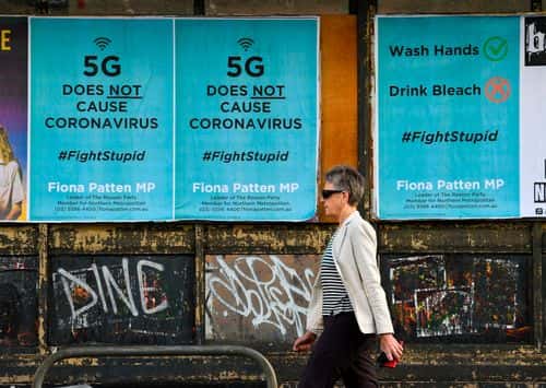 Tre plakater i Melbourne i juni 2020 tilbageviser misinformation om coronavirus med budskabet »5G does not cause coronavirus«. En person går forbi plakaterne, som opfordrer til håndvask og advarer mod at drikke blegemiddel.