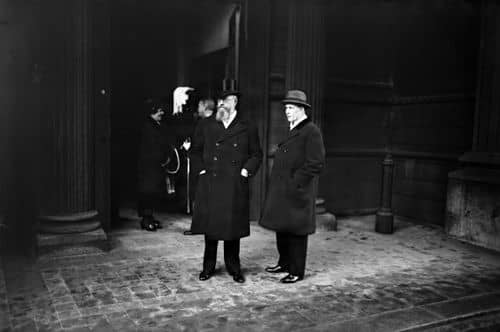 Sort-hvidt fotografi af to politikere i lange frakker og hatte foran en bygning i København i 1930'erne. Billedet viser Thorvald Stauning og P. Munch i perioden omkring Kanslergadeforliget i 1933.
