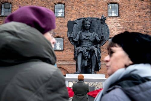 Tilskuere foran den syv meter høje skulptur I Am Queen Mary, som blev afsløret foran Vestindisk Pakhus i København den 31. marts 2018. Skulpturen forestiller Mary Thomas, der stod i spidsen for arbejderopstanden på St. Croix i 1878.