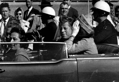 Præsident John F. Kennedy vinker fra sin åbne bil cirka ét minut før han blev skudt den 22. november 1963 i Dallas. Ved siden af ham sidder førstedame Jacqueline Kennedy.