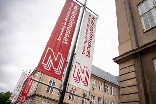 To høje bannere foran Statens Museum for Kunst med teksten “Nationalmuseet” og “National Museum of Denmark” samt en stor “N”-grafik. Bannere er monteret på en lygtepæl, med museumsbygninger i baggrunden.