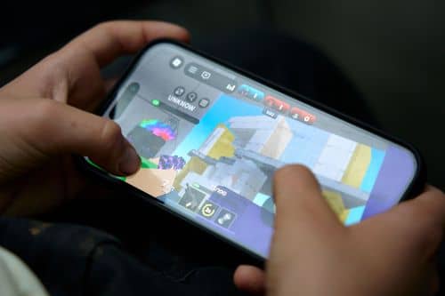Nærbillede af hænder, der holder en smartphone med spillet Roblox åbent på skærmen. Billedet illustrerer børn og unges brug af digitale spil og online platforme.