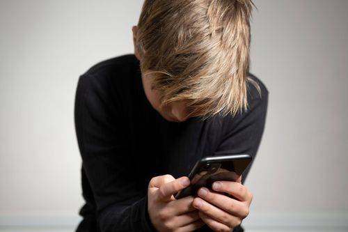 Dreng kigger på mobiltelefon