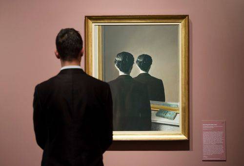 Udstillingsgæst betragter værk af den belgiske surrealist René Magritte