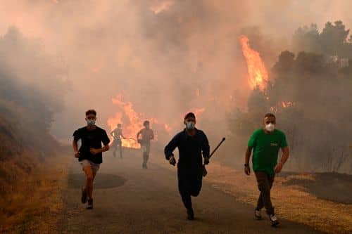 Mennesker løber forbi et afbrændt område under en skovbrand nær landsbyen Larouco i Ourense‑provinsen i det nordvestlige Spanien den 13. august 2025, hvor store brande under en langvarig hedebølge hærgede i Spanien og andre dele af Europa.