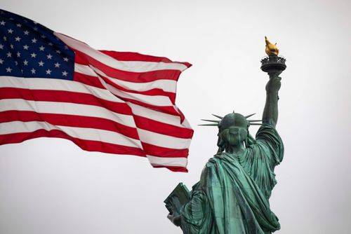Frihedsgudinden i New York med det amerikanske flag i forgrunden.