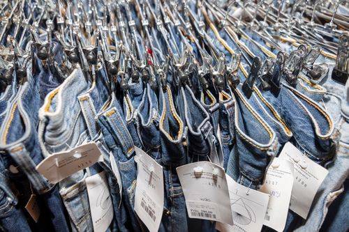 Række af jeans på bøjler i en genbrugsbutik.