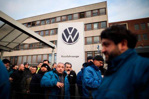 Ansatte hos Volkswagen foran fabrik med Volkswagens logo