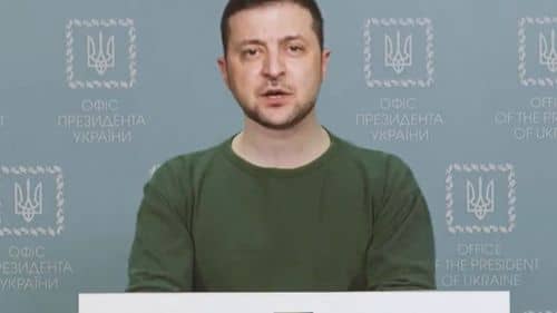 Skærmbillede fra en deepfake-video fra juni 2022, hvor Ukraines præsident Volodymyr Zelenskyj ses i grøn trøje bag et podium foran en blå baggrund med statsvåben og teksten “Office of the President of Ukraine”.