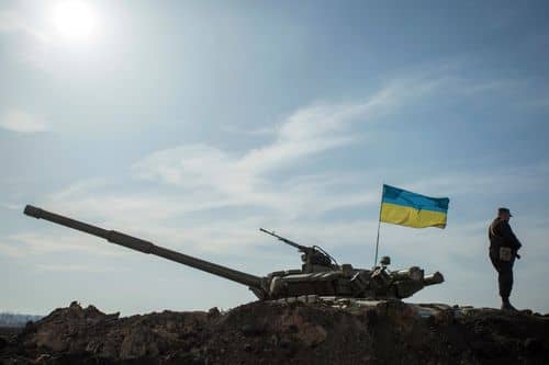 En soldat står ved siden af en kampvogn med et ukrainsk flag