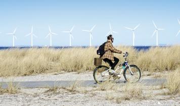 Ung mand på cykel i Amager Strandpark - med vindmøller i baggrunden.