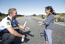 Dansk politibetjent leger med en pige som var en del af flygtningestrømmen på motorvejen E45 den 9. september 2015.