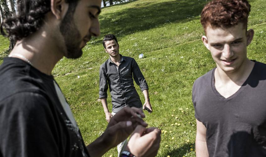 Tre unge mænd på græsplæne foran Snoghøj Højskole