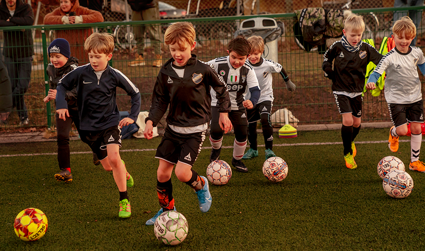 Børn til fodboldtræning løber med bolde
