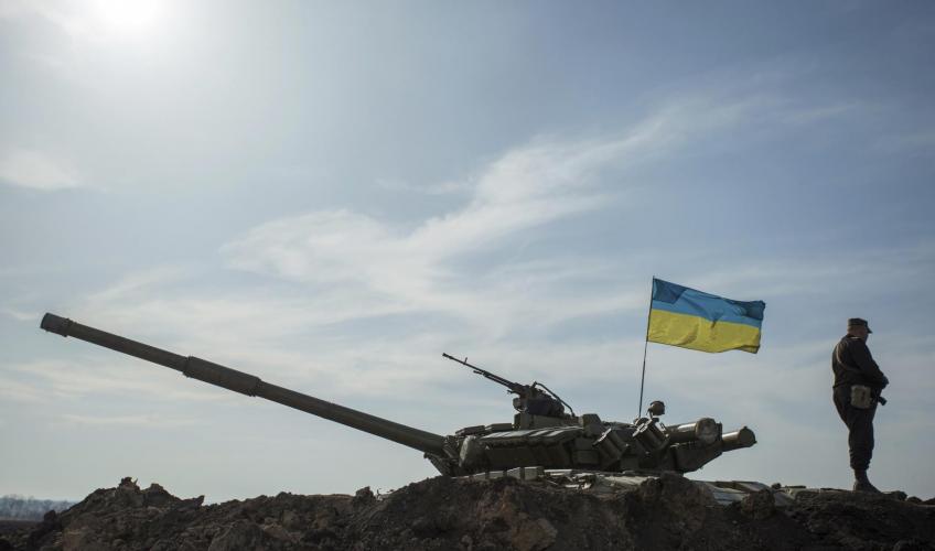En soldat står ved siden af en kampvogn med et ukrainsk flag