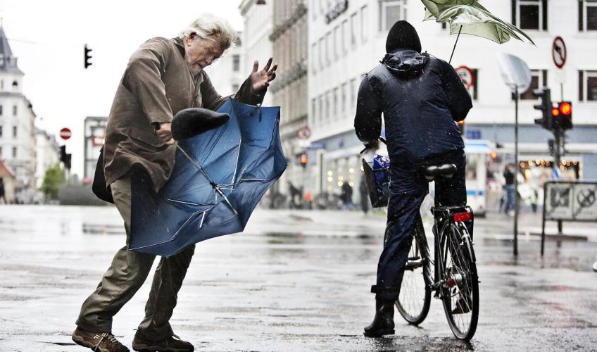 Fodgænger og cyklist i regnvejr. 2023 blev det mest regnfulde år i Danmark nogensinde.
